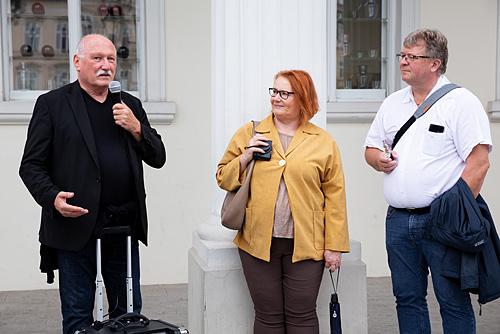 Fotografie Inspirationen. Lois Lammerhuber steht neben zwei Fotokursteilnehmern uns spricht in ein Mikrofon.