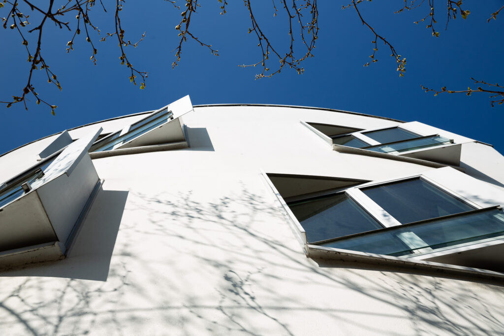 Wir fangen Schattenspiele an den Fassaden und der Kontrast zwischen klarer Architektur und wild wachsender Natur ein.